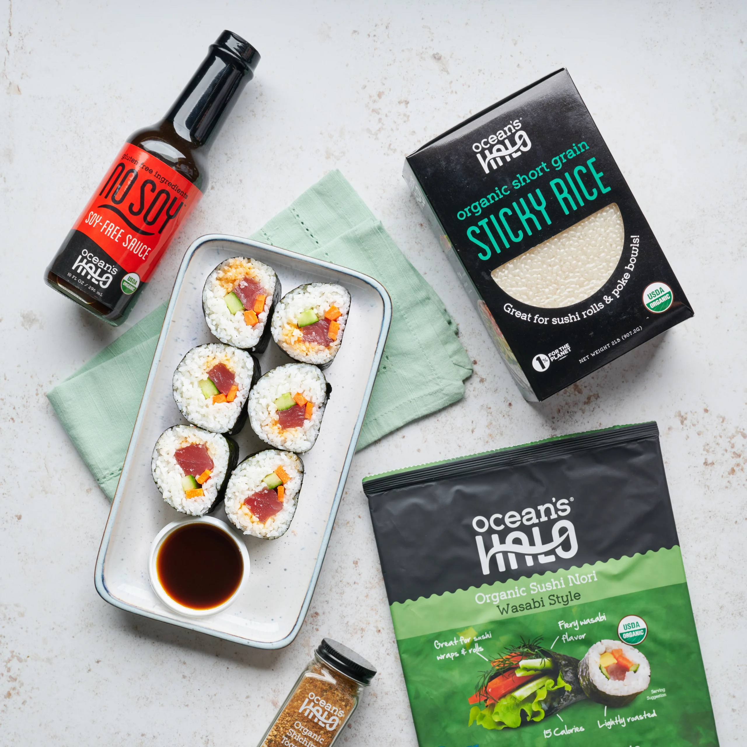 Fresh tuna sushi rolls served with NoSoy sauce alongside Ocean's Halo Wasabi Sushi Nori and Sticky Rice packaging