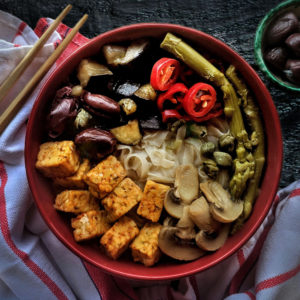 A bowl filled with fresh asparagus, sautéed mushrooms, and cubed tofu, showcasing a healthy, colorful dish.