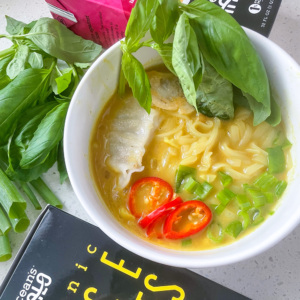 A bowl filled with colorful noodles, fresh vegetables, and aromatic herbs, showcasing a vibrant and healthy meal.