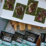 A white platter holds four seaweed snacks topped with iberico ham and caviar, surrounded by Ocean's Halo snack packs.