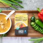 Ocean's Halo Malaysian Laksa Noodle Soup next to a bowl of soup and vegetables.